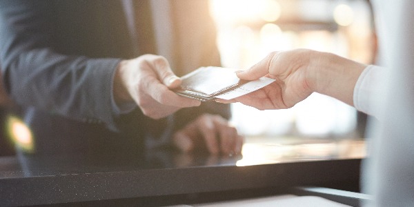 Businessman taking back his passport and ticket from hand of administrator after check-in