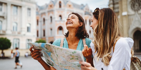 Fun, friends, travel and tourism concept. Beautiful girls looking for direction in the city